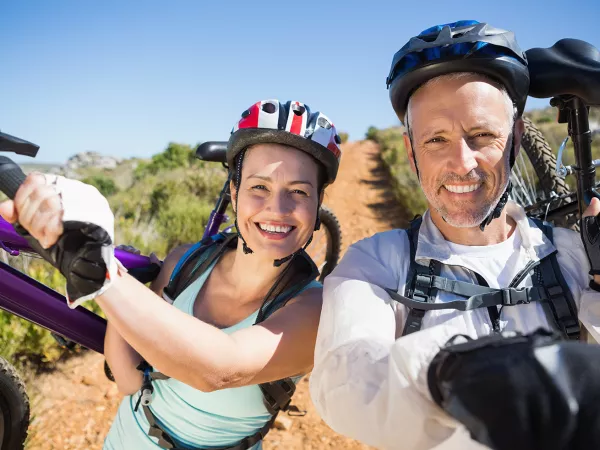 Women and man carrying bikes on a hill.