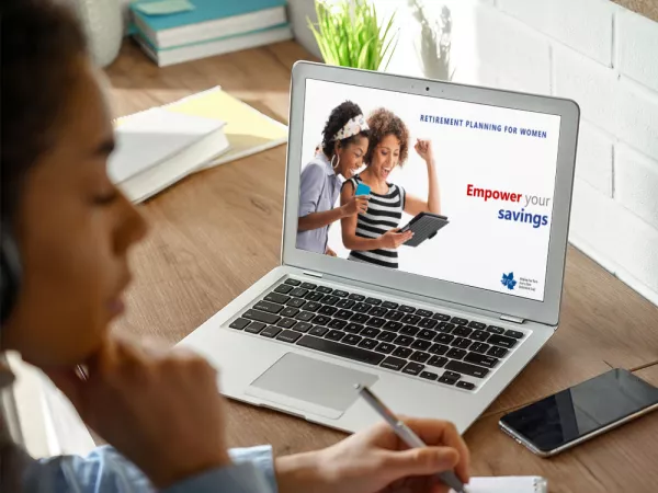 Woman watching video on computer and writing on tablet.