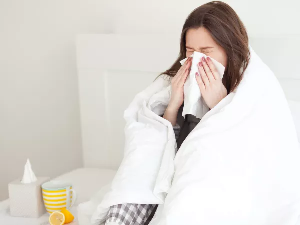 Woman in bed, blowing nose