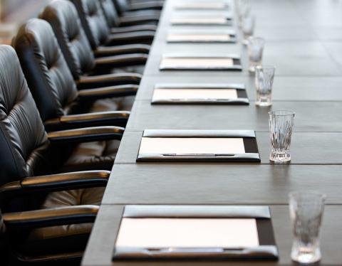 Executive conference table with papers, glasses, and leather chairs