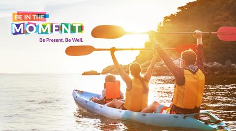 family kayaking along shore of large lake