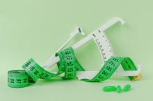 Photo of green tape measure, white body fat caliper, and three green capsules