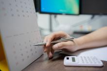 hand pointing and calendar next to calculator